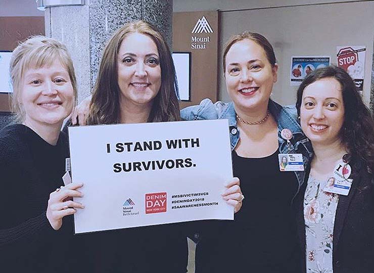 Social workers holding a sign saying “I stand with survivors”