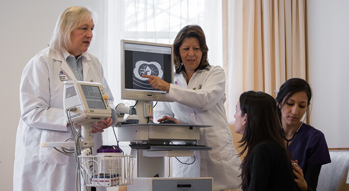 Two doctors explaining a scan to patient while nurse listens to patient