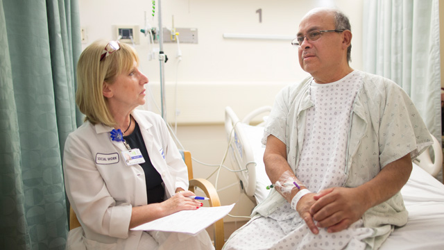 doctor listening to patient sitting on bed